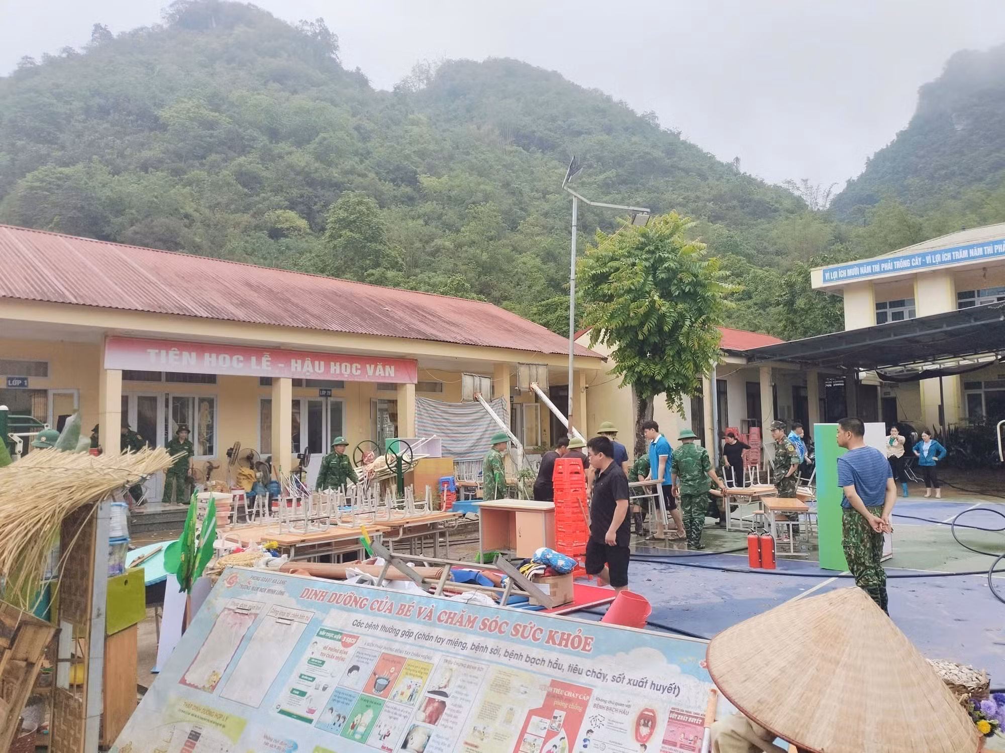 Người dân, lực lượng vũ trang tham gia khắc phục hậu quả sau mưa lớn tại Trường Mầm non và Tiểu học Minh Long. Ảnh: TTXVN phát