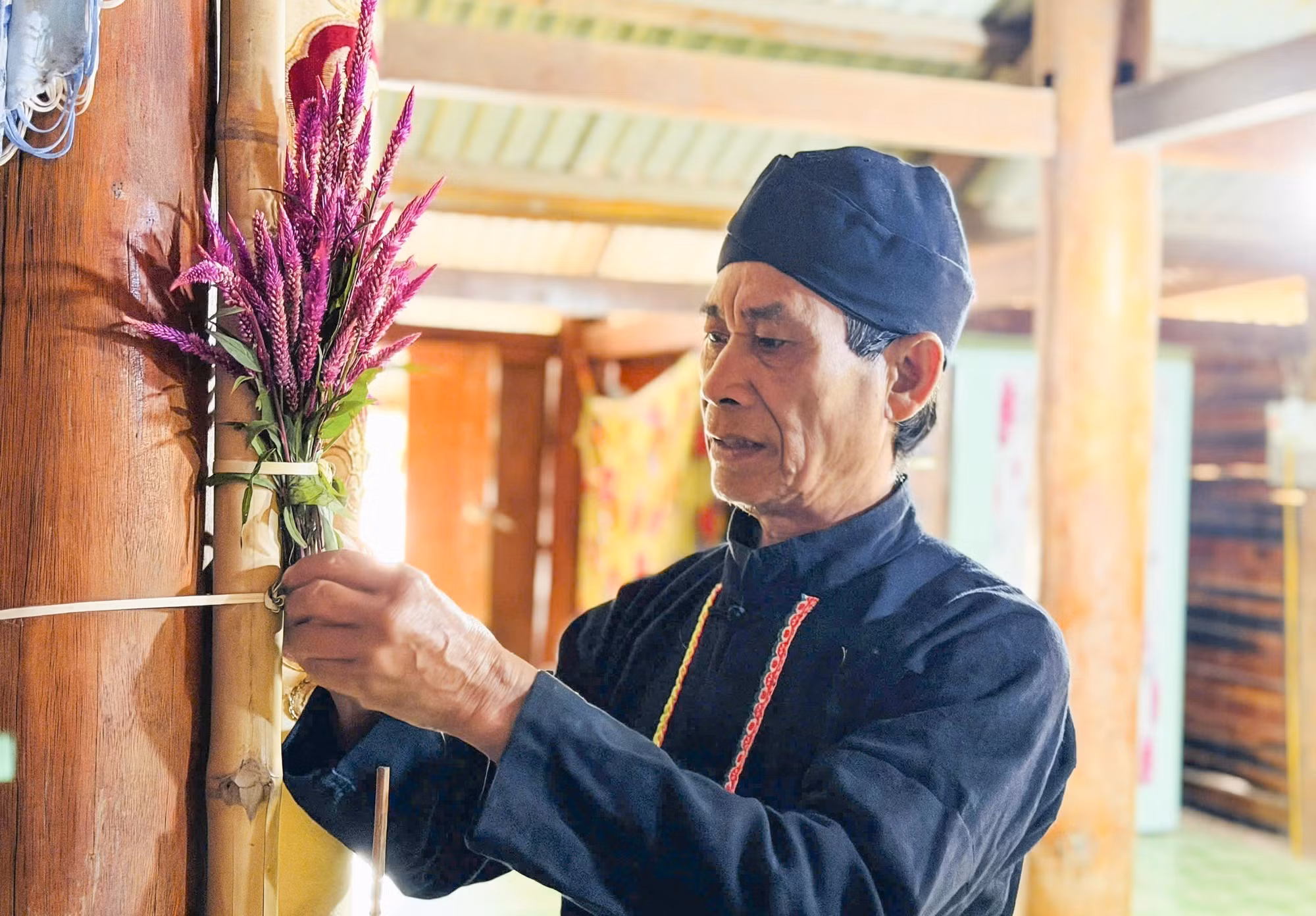 Thầy cúng buộc hoa mào gà trong nhà để thực hiện nghi thức cúng Tết. Ảnh: TTXVN phát