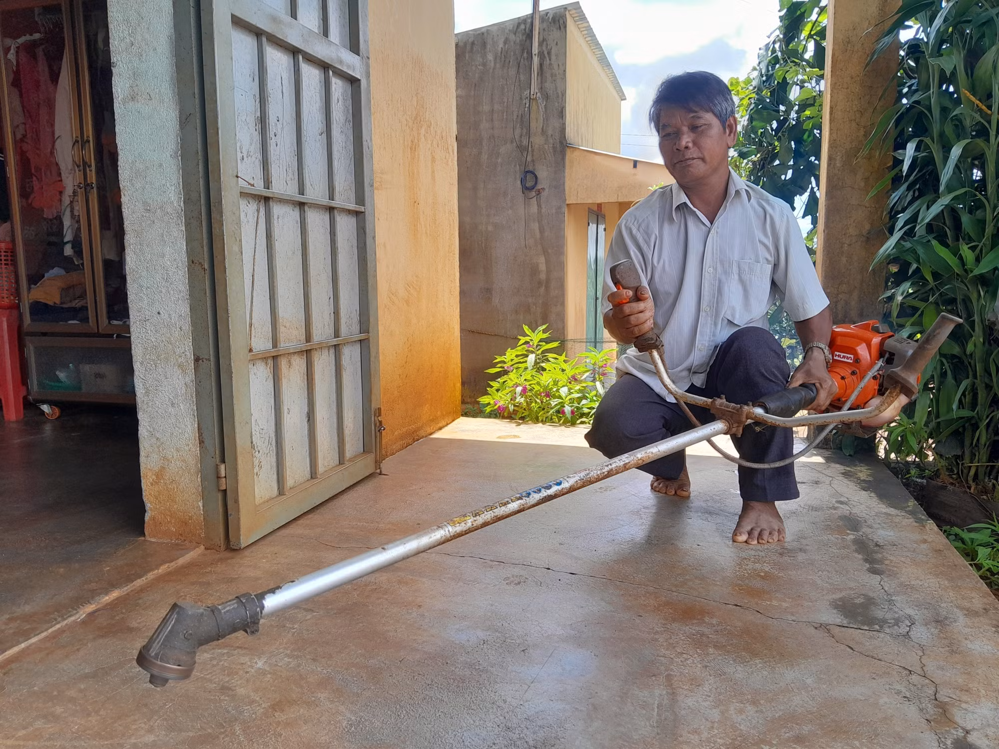Ông Điểu Lý tại khu dư cư Đắk Á (xã Bù Gia Mập, tỉnh Đồng Nai) kiểm tra nông cụ được chính quyền địa phương cấp làm công cụ sinh kế.