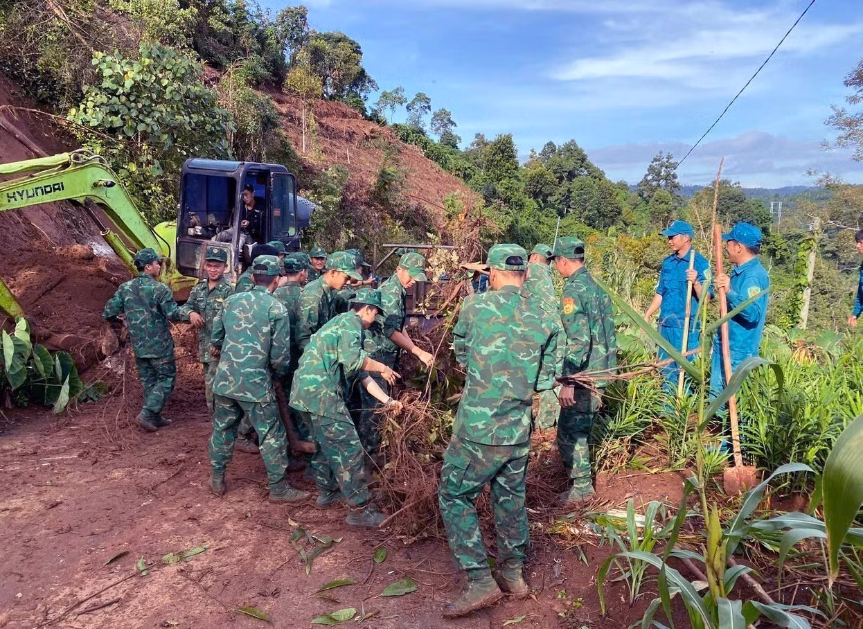 Lực lượng Đồn Biên phòng Cửa khẩu Thuận An hỗ trợ thu dọn đất, đá trên tuyến đường huyết mạch tại thôn Thuận Nam, xã Thuận An, tỉnh Lâm Đồng. Ảnh: TTXVN phát