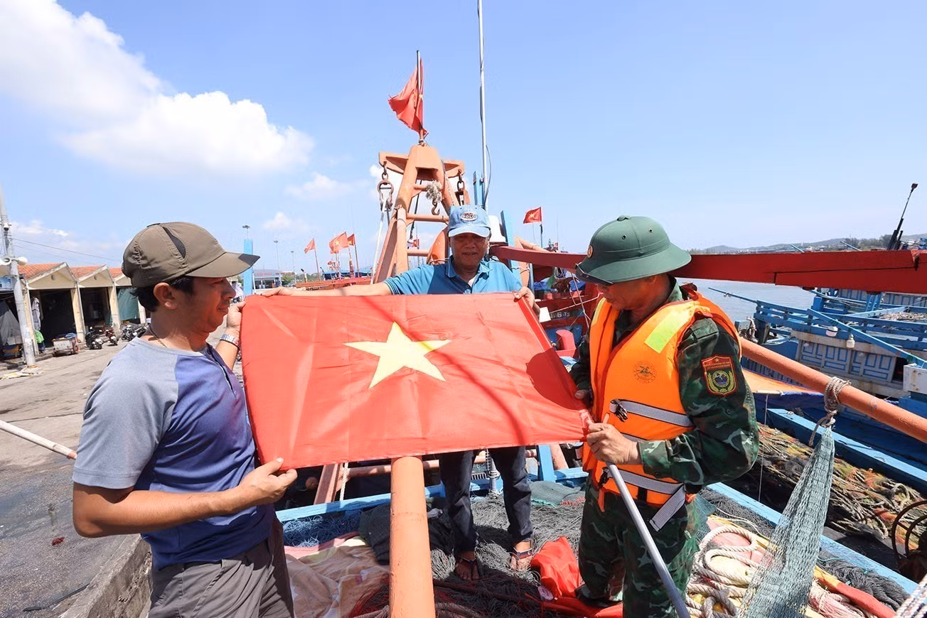 Bộ đội Biên phòng Hải Hoà tặng cờ Tổ quốc cho chủ tàu cá Nguyễn Văn Chiến, chuẩn bị ra khơi khai thác thuỷ sản, tại cảng cá Lạch Bạng, phường Hải Bình, tỉnh Thanh Hóa.