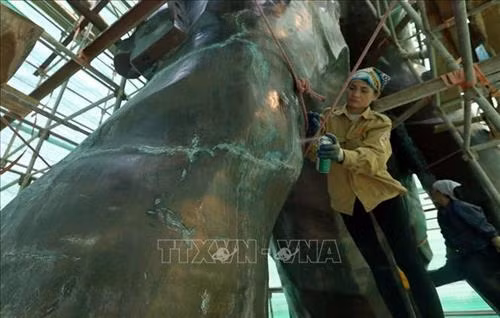 Các công nhân đang vệ sinh đánh bóng Tượng đài Chiến thắng Điện Biên Phủ. Ảnh: Phan Tuấn Anh - TTXVN