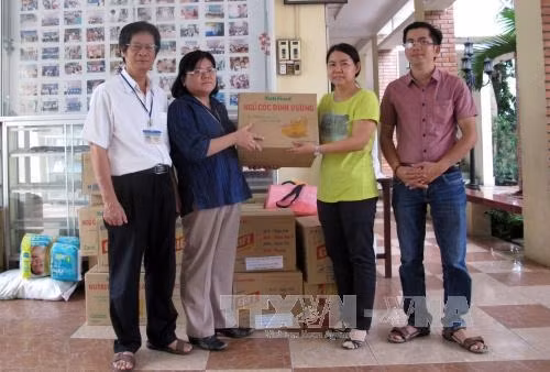 Đại diện Trung tâm phòng chống HIV/AIDS thành phố Hồ Chí Minh trao quà cho Trung tâm nuôi dưỡng bảo trợ trẻ em Linh Xuân. Ảnh: Phương Vy - TTXVN.