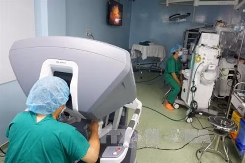 Bác sỹ Chuyên khoa II Hoàng Vĩnh Chúc, Trưởng khoa Ngoại Tiêu hóa Bệnh viện Bình Dân phẫu thuật viên chính điều khiển cánh tay robot quay 540 độ, di chuyển tự do ở 6 góc độ và vận động tinh vi để phẫu thuật cho bệnh nhân. Ảnh: Phương Vy - TTXVN.