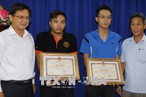 Lãnh đạo quận Thủ Đức trao bằng khen cho anh Dương Minh Quang và anh Bùi Văn Tiến. Ảnh: Hoàng Hải-TTXVN
