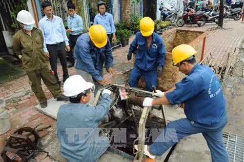 Các công nhân Công ty thoát nước đô thị tiến hành vớt rác thải tại các cống trên đường Nguyễn Hữu Cảnh, quận Bình Thạnh. Ảnh: An Hiếu - TTXVN