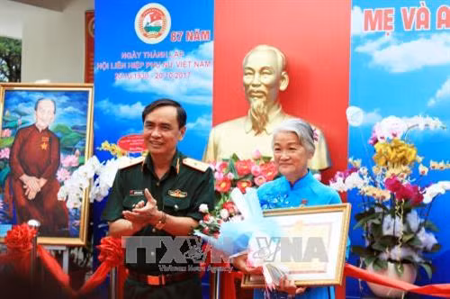 Thiếu tướng Nguyễn Minh Hoàng, Phó Chính ủy Quân khu 7 tặng Bằng khen của Bộ Tư lệnh Quân khu 7 cho họa sỹ Đặng Ái Việt. Ảnh : Xuân Khu-TTXVN