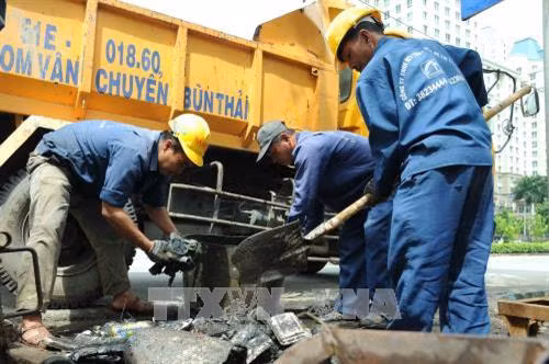Các công nhân Công ty thoát nước đô thị tiến hành vớt rác thải tại các cống trên đường Nguyễn Hữu Cảnh, quận Bình Thạnh. Ảnh: An Hiếu - TTXVN