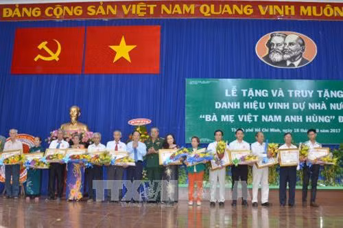 Phó Bí thư Thường trực Thành ủy thành phố Hồ Chí Minh Tất Thành Cang trao tặng danh hiệu Bà Mẹ Việt Nam Anh hùng cho thân nhân các mẹ. Ảnh: Thanh Vũ - TTXVN