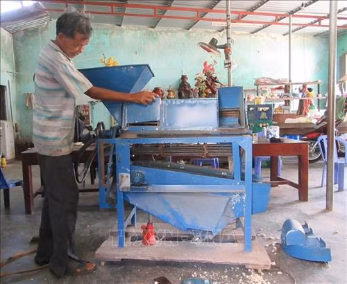 Ông Thái Văn Âu với máy “3 trong 1” có thể tách vỏ ngô, đậu, tuốt lúa. Ảnh: Nguyễn Thành – TTXVN