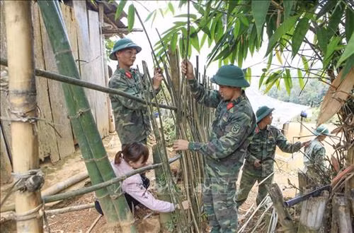 Các chiến sĩ cùng giáo viên làm lại hàng rào cho điểm trường. Ảnh: Xuân Tư – TTXVN