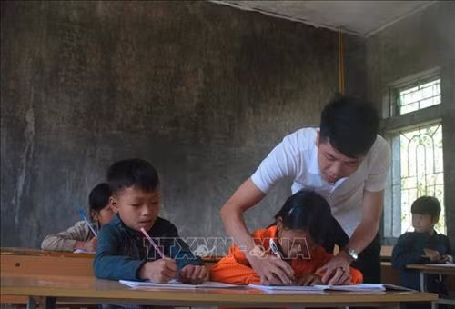 Thầy giáo Hoàng Văn Duy hướng dẫn học sinh viết bài tại điểm trường Hò Lù, xã Khánh Xuân (Bảo Lạc, Cao Bằng). Ảnh: Chu Hiệu - TTXVN