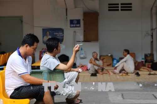 Vô tư nhả khói trong khuôn viên bệnh viện dù bảng cấm hút thuốc ngay bên cạnh. Ảnh: Đinh Hằng – TTXVN