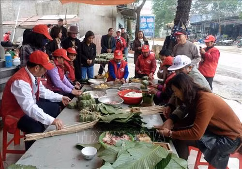Các thành viên trong Đội tình nguyện viên Chữ thập đỏ Tân Hòa tập trung gói bánh chưng tặng cho người nghèo đón Tết. Ảnh: Quang Đán – TTXVN