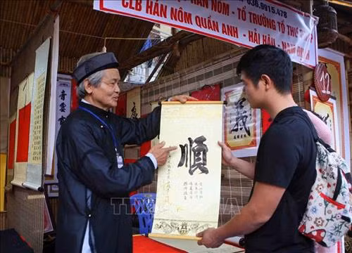 Ông đồ tặng chữ, giải nghĩa chữ đầu Xuân tại khu Hồ Văn (Văn Miếu – Quốc Tử Giám) trong ngày khai mạc. Ảnh: Thanh Tùng-TTXVN