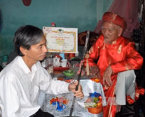 Nghệ nhân Lữ Hữu Thi (bên phải), truyền những ngón nghề cho người con trai của mình là ông Lữ Viết Minh. Ảnh: Quốc Việt - TTXVN