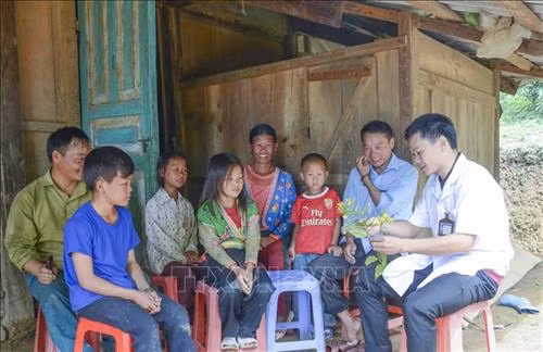 Cán bộ y tế xã tuyên truyền với người dân về tác hại của cây lá ngón. Ảnh: Xuân Tư – TTXVN