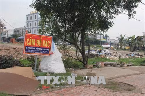 Ngay cạnh tấm biển “Cấm đổ rác” là cả một bãi rác lộ thiên (xã Đức Hòa Hạ, Đức Hòa). Ảnh: Bùi Giang – TTXVN