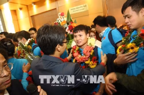 Phó Thủ tướng Vũ Đức Đam tặng hoa chúc mừng cầu thủ Quang Hải. Ảnh: TTXVN phát