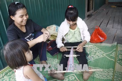 Chị em hội viên thuộc Chi hội Liên hiệp phụ nữ làng Nghe Nhỏ tập trung dệt trước nhà để tranh thủ trao đổi, học hỏi các họa tiết hoa văn mới. Ảnh: Hồng Điệp - TTXVN