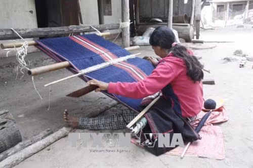 Chị em phụ nữ tranh thủ giờ nghỉ trưa để dệt thổ cẩm. Ảnh: Hồng Điệp – TTXVN