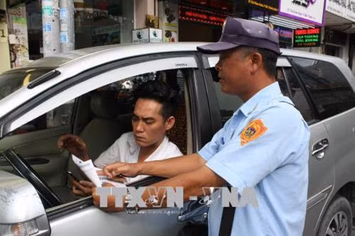Nhân viên tổ thu phí xe ô tô quận 1 hướng dẫn lái xe cách thanh toán phí qua ứng dụng My Parking trên đường Thủ Khoa Huân. Ảnh: Tiến Lực – TTXVN