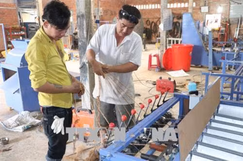 Anh Lê Văn liêm với sáng chế máy se chỉ sơ dừa 8 trục và máy xe thừng không nối. Ảnh: Huỳnh Phúc Hậu - TTXVN