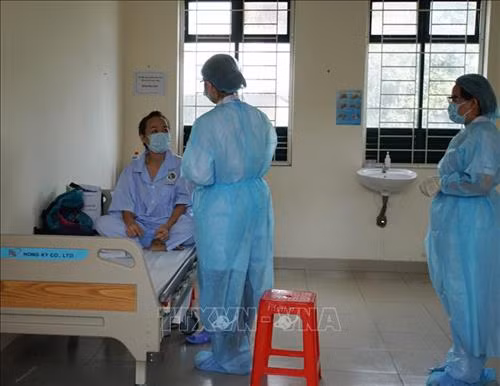 Nhân viên y tế thăm hỏi tình hình sức khỏe người cách ly tại khu cách ly Trung tâm Quận 2. Ảnh: Đinh Hằng – TTXVN