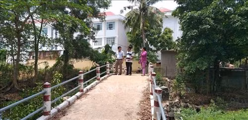 Ông Nguyễn Ngọc Sơn (giữa) cùng đại diện chính quyền địa phương trên cây cầu bê tông mới được xây dựng. Ảnh: Lê Xuân-TTXVN