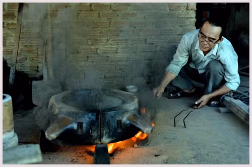 Nghệ nhân Dương Quốc Thuần đốt vỏ khuôn bằng giẻ dầu để tạo một lớp muội đen chống dính.
