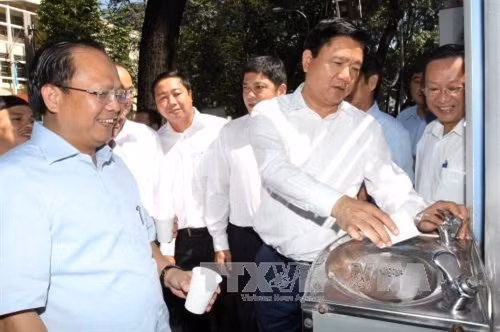 Bí thư Thành ủy Đinh La Thăng và các đồng chí trong đoàn công tác dùng thử nước sạch uống tại vòi. Ảnh: Thanh Vũ – TTXVN