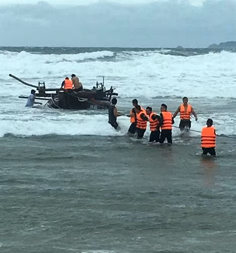 Cán bộ, chiến sĩ Đồn biên phòng Cửa Đại kéo tàu bị trôi dạt ngoài biển vào bờ. Ảnh: Đổ Trưởng-TTXVN