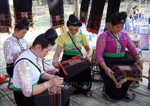 Phụ nữ dân tộc Thái ở Tây Bắc trong trang phục truyền thống (váy, áo cóm, tằng cẩu) đang thêu thùa, may vá thổ cẩm. Ảnh: Xuân Tiến – TTXVN