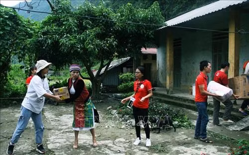 Cô giáo ở Trường Tiểu học Phố Cáo nhận quà tặng của nhóm từ thiện Cầu nối trái tim. Ảnh: Trần Quang Vinh - TTXVN