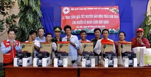 Phó Chủ tịch Hội CTĐ Thành phố Hồ Chí Minh Trần Văn Tuấn (trái) và Đoàn công tác hội CTĐ thành phố tặng quà Tết và bộ thiết bị thông tin liên lạc ICOM 718 cho 6 gia đình ngư dân có hoàn cảnh khó khăn tại huyện Cần Giờ, Thành phố Hồ Chí Minh. Ảnh: Thế Anh - TTXVN