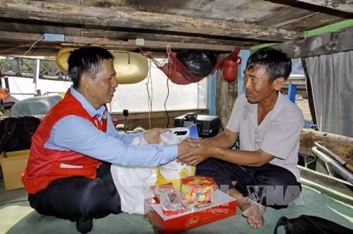 Phó Chủ tịch Hội CTĐ Thành phố Hồ Chí Minh Trần Văn Tuấn (trái) và Đoàn công tác hội CTĐ thành phố tặng quà Tết và bộ thiết bị thông tin liên lạc ICOM 718 cho gia đình ngư dân Lê Văn Quang (ngụ tại thị trấn Cần Thạnh, huyện Cần Giờ) có hoàn cảnh đặc biệt khó khăn. Ảnh: Thế Anh - TTXVN