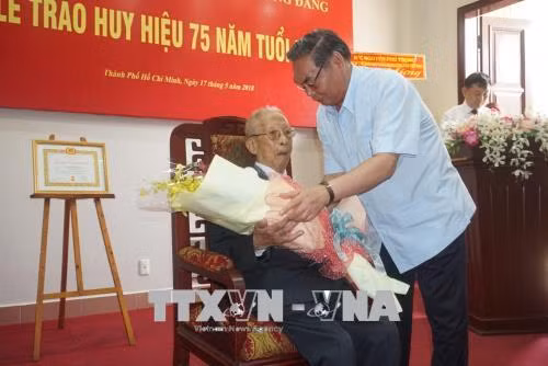 Đồng chí Lê Hồng Anh, nguyên Uỷ viên Bộ Chính trị, nguyên Thường trực Ban Bí thư tặng hoa chúc mừng đồng chí Trần Quốc Hương nhận Huy hiệu 75 tuổi Đảng. Ảnh: Anh Tuấn - TTXVN