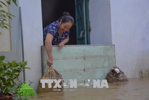 Người dân chặn khỏi nước ngập vào nhà. Ảnh: Xuân Tư - TTXVN