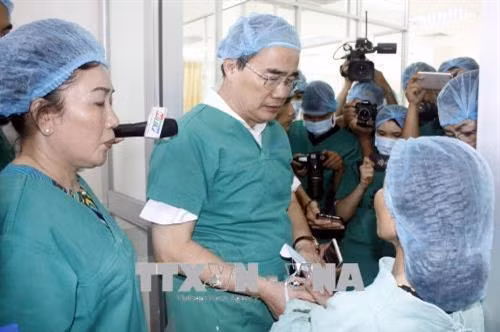 Bí thư Thành ủy Nguyễn Thiện Nhân động viên vợ anh Trần Văn Hoàng, Đội trưởng Đội "hiệp sĩ đường phố" quận Tân Bình, đang điều trị tại Bệnh viện 115. Ảnh: Hoàng Hải - TTXVN