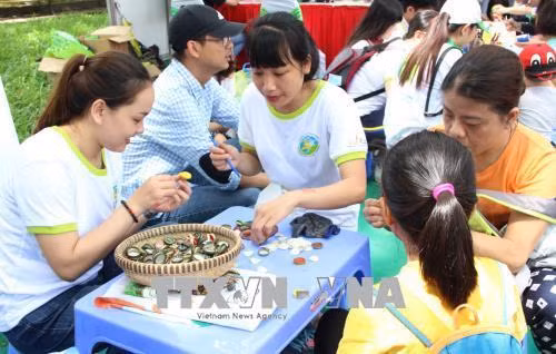 Người dân trải nghiệm làm đồ chơi từ rác thải. Ảnh: Xuân Dự - TTXVN