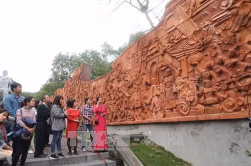 Du khách tham quan bức phù điêu được làm bằng đất nung như một pho sử lớn tại huyện Kim Môn. Ảnh: Hiền Anh- TTXVN.