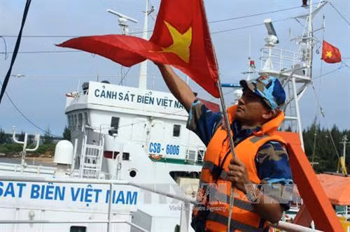 Chiến sĩ tàu Cảnh sát biển 9002 kéo cờ Tổ quốc, chuẩn bị xuất phát đi làm nhiệm vụ. Ảnh: TTXVN phát.