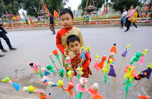 Các em bé thích thú với trò chơi dân gian nặn tò he tại lễ hội. Ảnh: Phạm Kiên - TTXVN