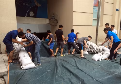 Diễn tập phương án đắp bao cát hàn khẩu chống ngập trong trong trường hợp mưa to nước tràn vào tầng hầm toà nhà. Ảnh: Hải Anh- TTXVN