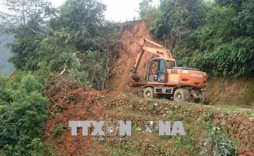 Các đơn vị tích cực huy động máy móc và nhân lực để cố gắng thông tuyến đường vào xã Pa Vệ Sủ. Ảnh: Việt Hoàng - TTXVN