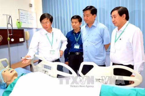 Bí thư Thành ủy Đinh La Thăng tham quan phòng thực hành của trường. Ảnh: Mạnh Linh - TTXVN