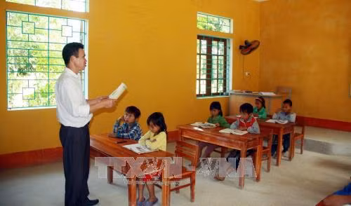 Thầy Nguyễn Trọng Tài với học sinh điểm trường Cọ Cỏm. Ảnh: Quang Cường – TTXVN