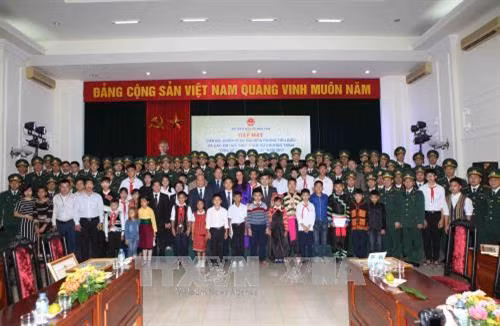 Các đại biểu với 60 cán bộ, chiến sĩ Bộ đội Biên phòng tiêu biểu và tặng quà cho các em học sinh có hoàn cảnh đặc biệt khó khăn được đỡ đầu. Ảnh: Quý Trung – TTXVN