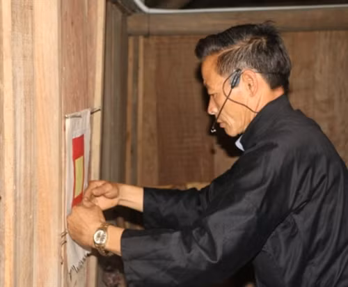 Chủ nhà dán giấy mới trên bàn thờ Xử Ka.