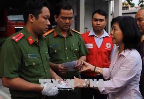 Bà Đặng Hồng Nhung, đại diện Trung ương Hội Chữ thập đỏ Việt Nam đã trao tiền hỗ trợ cho chiến sĩ công an phòng cháy chữa cháy bị thương trong khi chữa cháy sáng 23/3. Ảnh: Xuân Dự - TTXVN